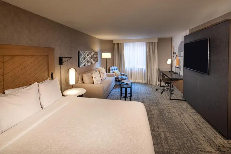 Une chambre d'hôtel lumineuse avec un lit, un canapé et un espace de travail.