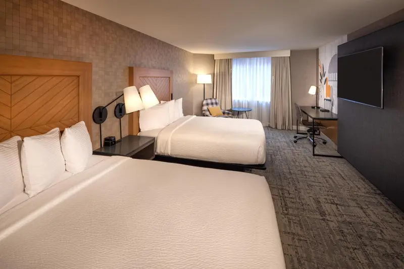 Une chambre d'hôtel avec deux lits et un espace bureau.
