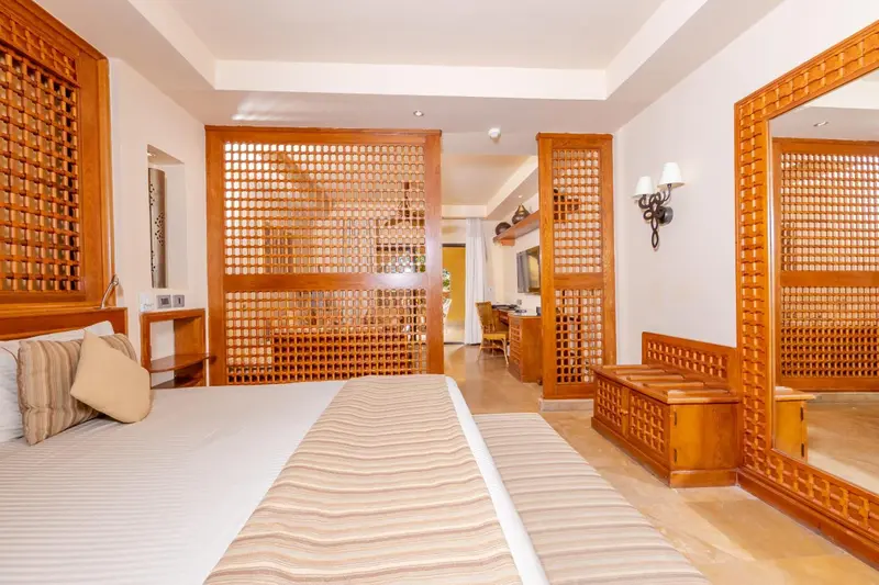 Chambre lumineuse avec un grand lit et des éléments décoratifs en bois.