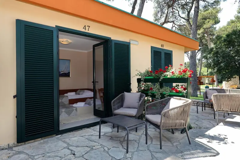 Terrasse devant une chambre avec un lit visible à l'intérieur.