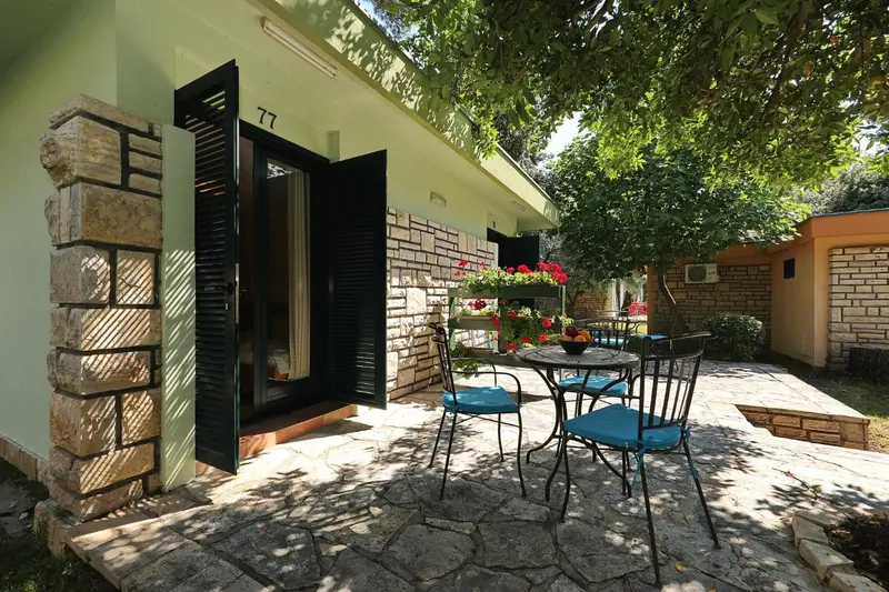 Une terrasse avec une table et des chaises devant une porte ouverte.