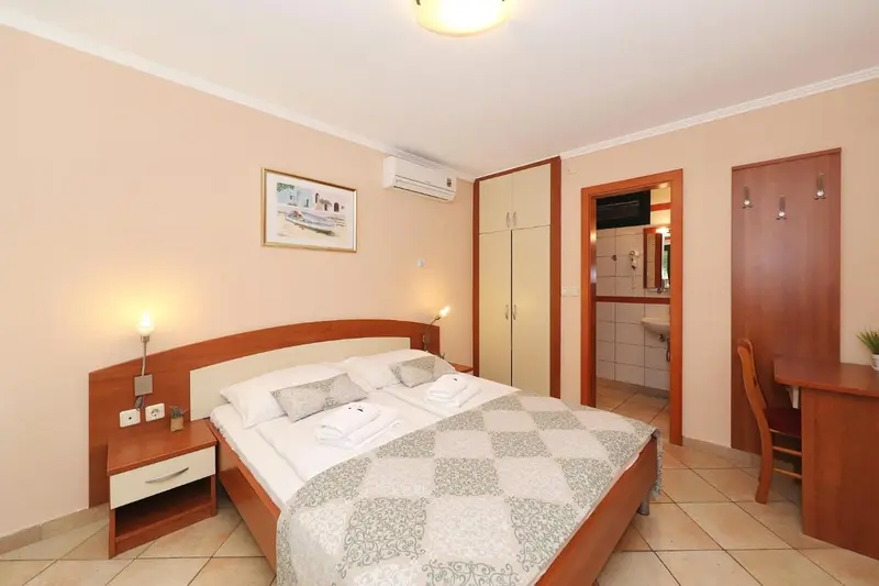 Une chambre lumineuse avec un grand lit et un accès à une salle de bain.