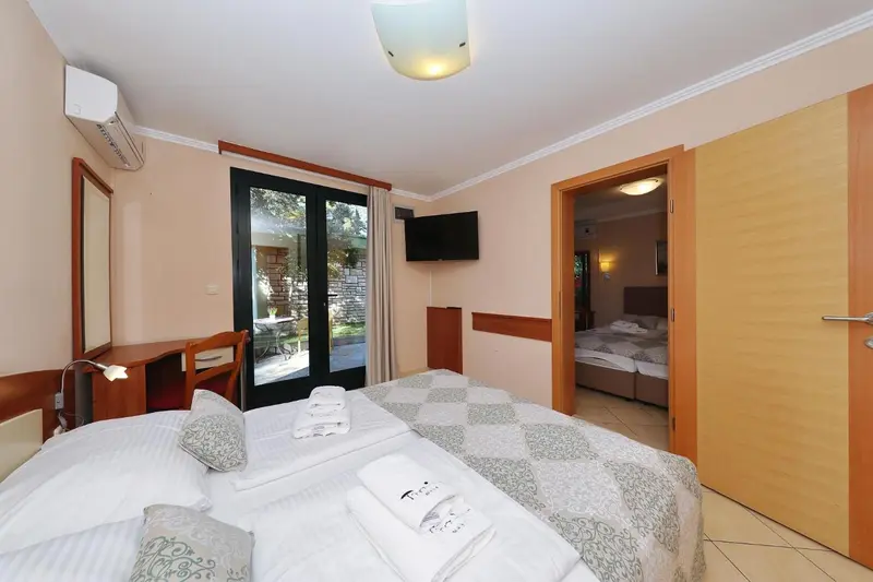 Une chambre lumineuse avec un lit fait et un accès à une terrasse.
