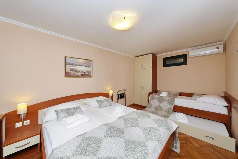 Une chambre lumineuse avec deux lits simples et un lit double.