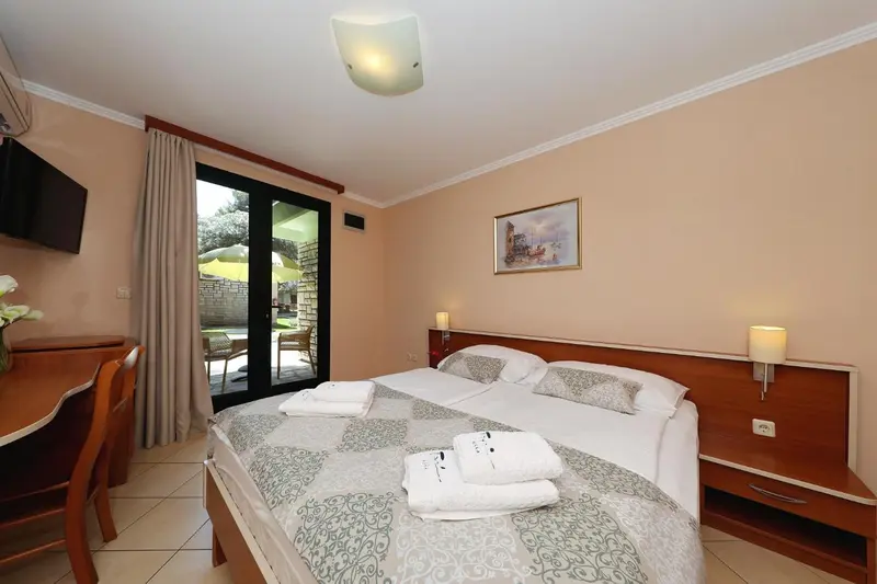 Une chambre lumineuse avec un lit double et un accès à une terrasse.