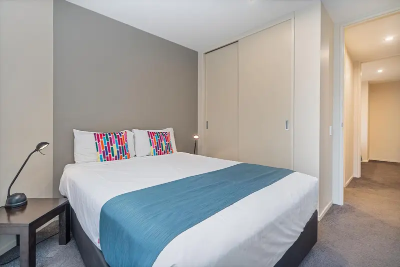 Une chambre moderne avec un grand lit recouvert d'une courtepointe bleue et de coussins colorés.