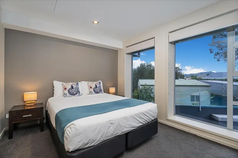 Une chambre lumineuse avec un grand lit et une vue sur un paysage verdoyant.