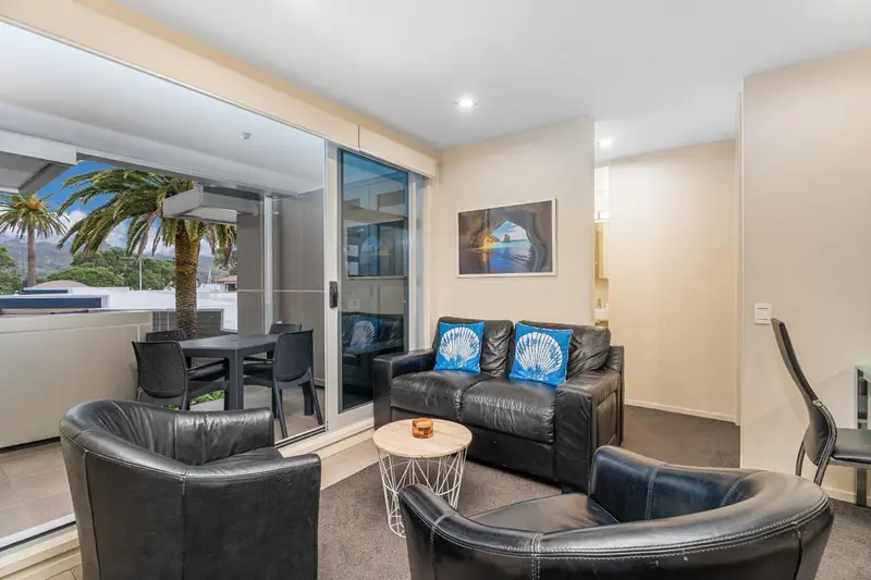 Un salon moderne s'ouvre sur une terrasse avec vue sur la végétation.