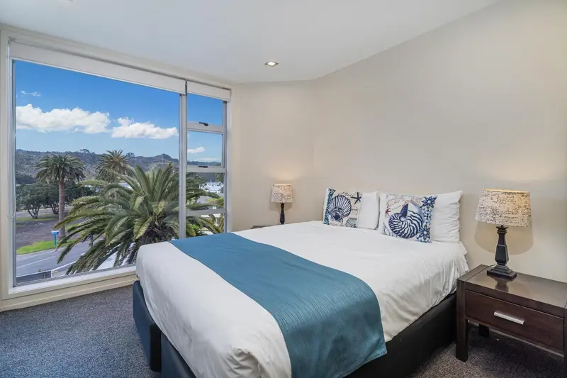 Une chambre lumineuse avec un grand lit et une vue sur la végétation.