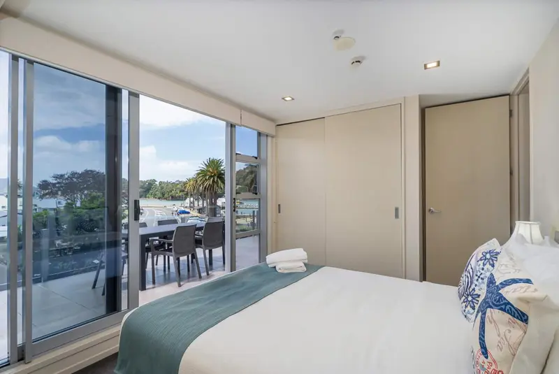 Une chambre lumineuse avec un grand lit donnant sur une vue mer et une terrasse.