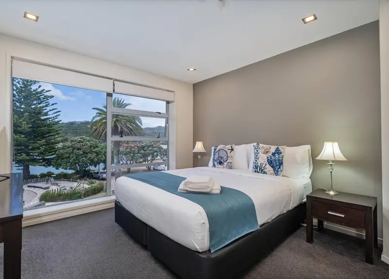 Une chambre lumineuse avec un grand lit et une vue sur la végétation.