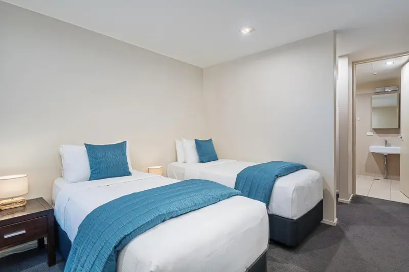 Une chambre lumineuse avec deux lits simples et une décoration sobre.