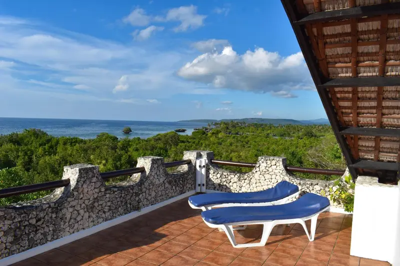 Terrasse avec chaises longues donnant sur une vue panoramique de la mer et de la végétation.