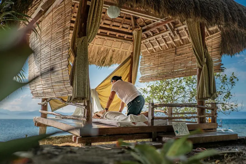 Un massage en plein air se déroule sur une plateforme en bois avec vue sur la mer.