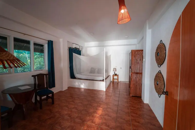 Une chambre lumineuse avec un lit à baldaquin et une table près de la fenêtre.