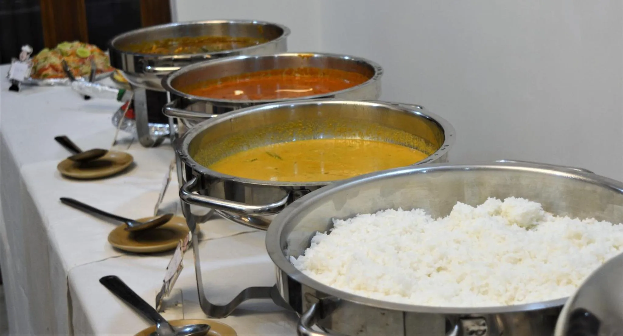 Présentation de plats chauds dans des récipients en métal sur un buffet.
