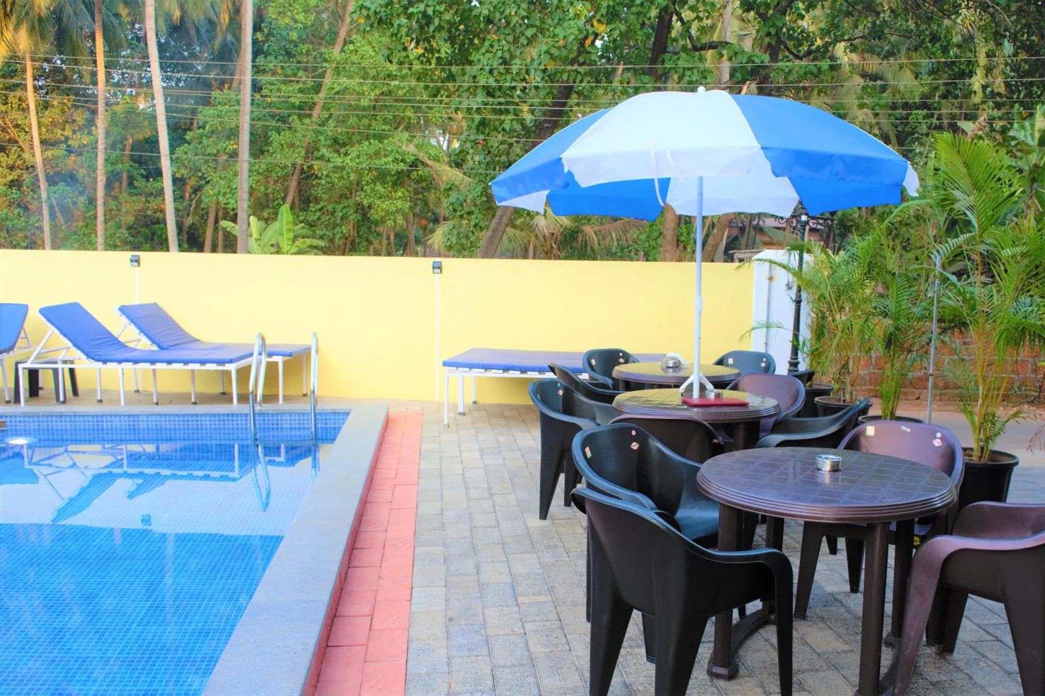 Terrasse avec transats et tables près d'une piscine.