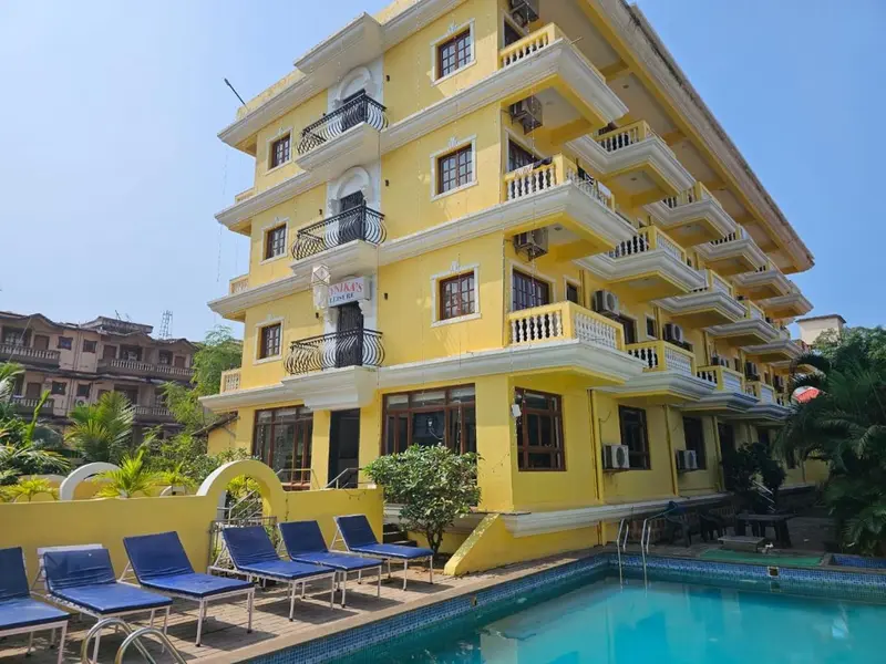 Façade jaune d'un bâtiment avec des balcons et des transats bleus près d'une piscine.