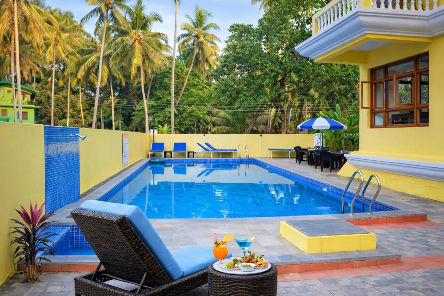 Deux transats bleus bordent une piscine rectangulaire turquoise.