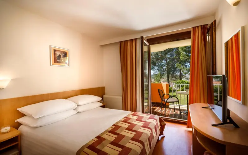 Une chambre lumineuse avec un lit double et un accès à un balcon.
