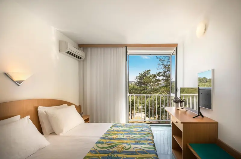 Une chambre lumineuse avec un lit et un accès à un balcon.