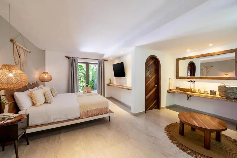 Une chambre lumineuse avec un grand lit et un accès à une salle de bain.