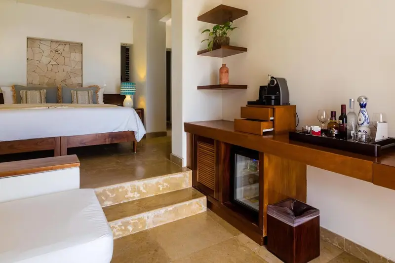 Une chambre lumineuse avec un grand lit et un coin bar.