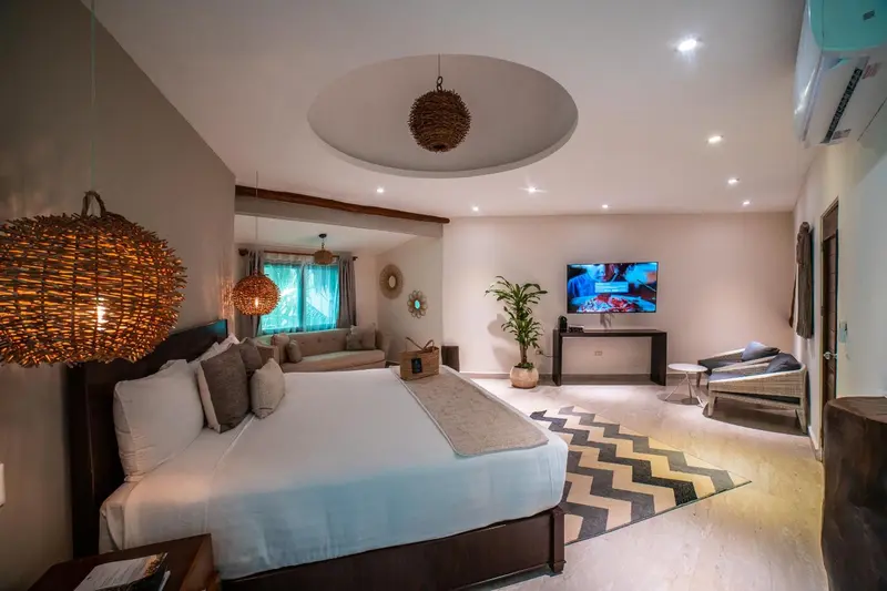 Une chambre lumineuse avec un grand lit et un espace salon.