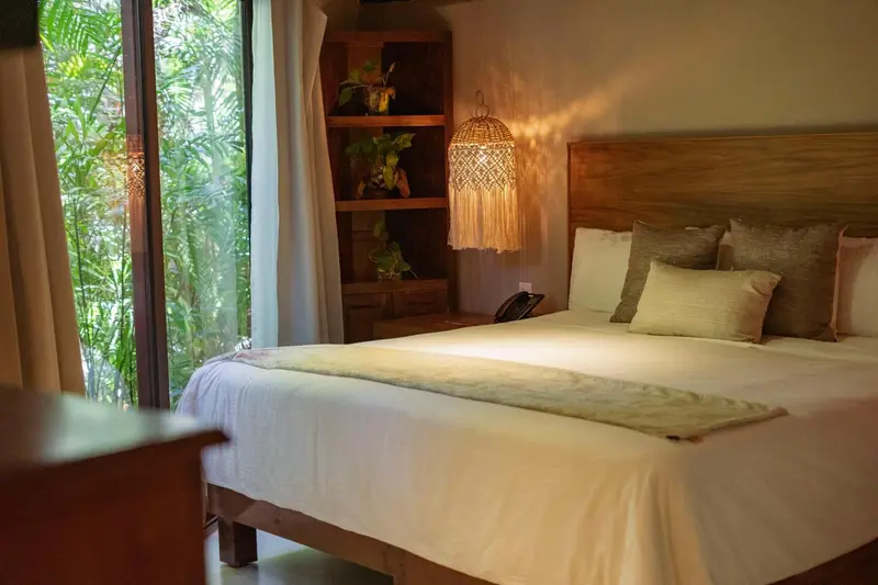 Une chambre lumineuse avec un grand lit et une vue sur la végétation.