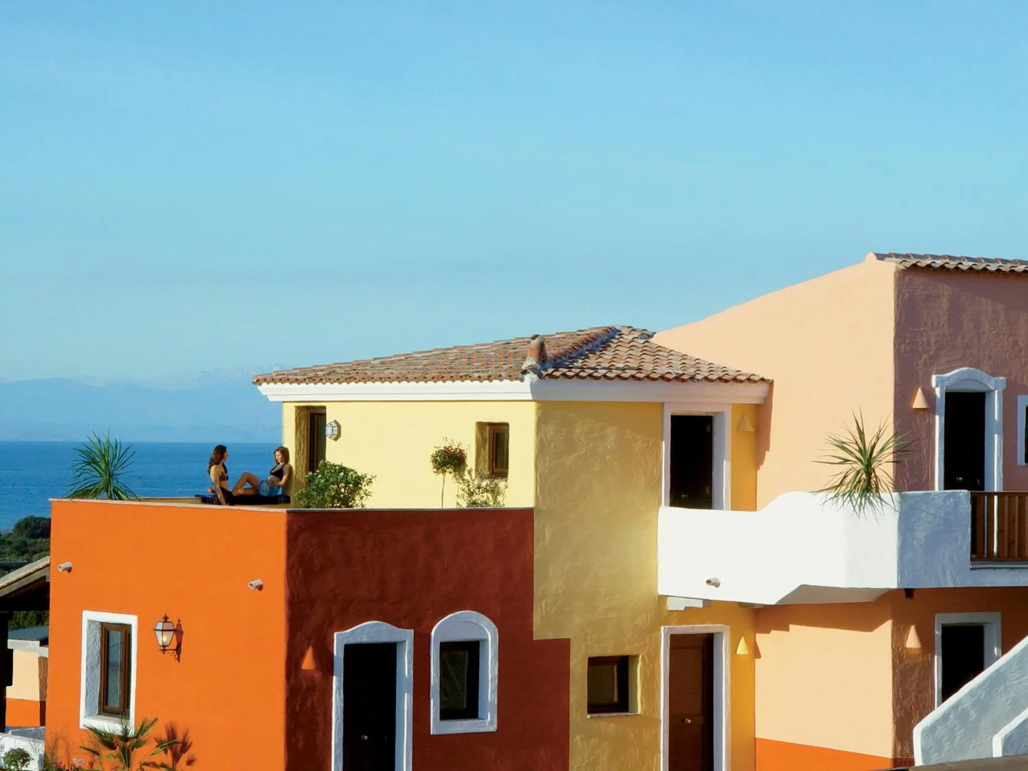 Bâtiments colorés avec des terrasses ensoleillées donnant sur la mer.