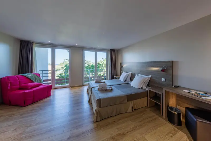 Une chambre lumineuse avec un canapé rose et un grand lit.