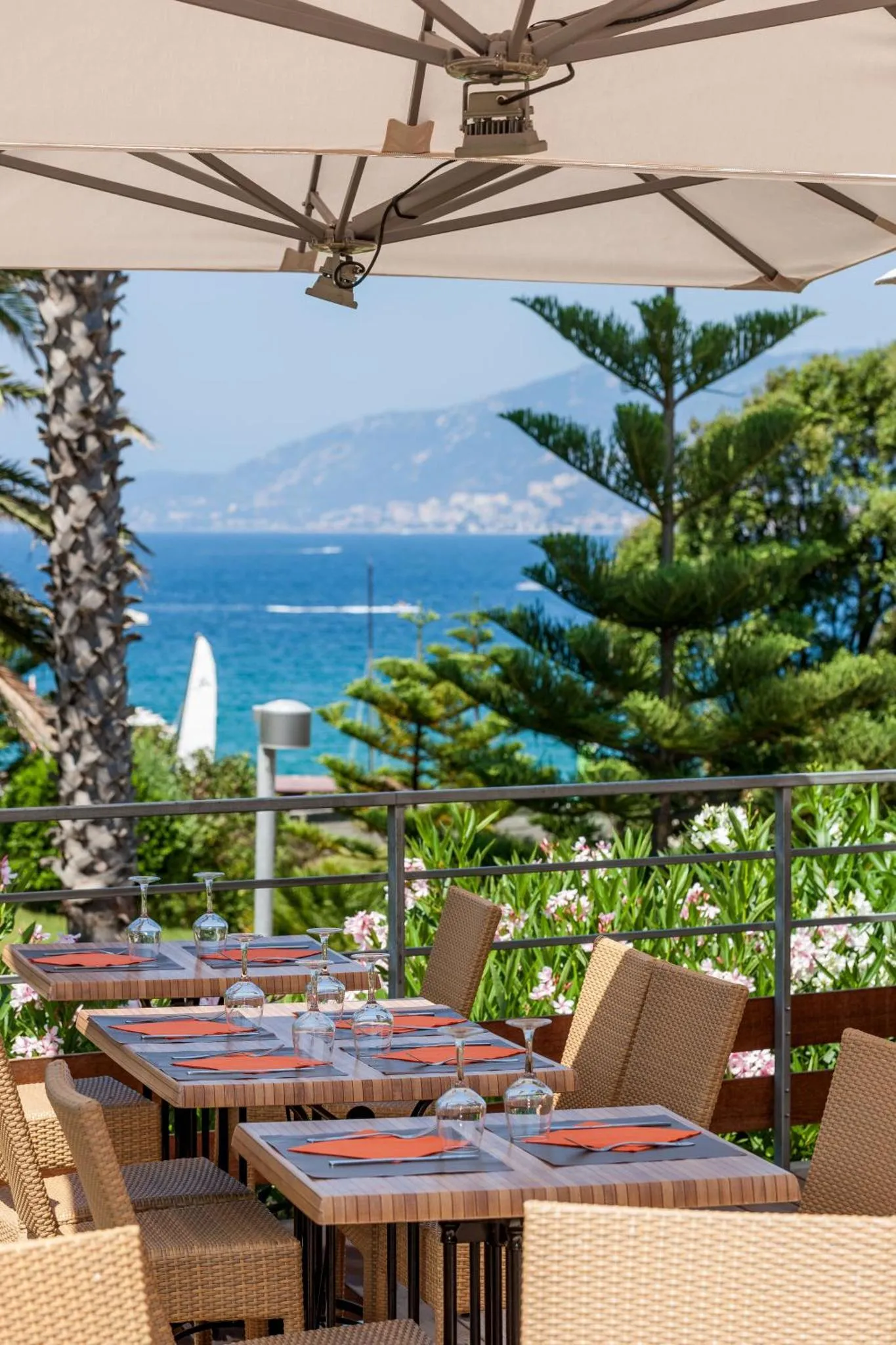 Terrasse ombragée avec tables et chaises donnant sur la mer.