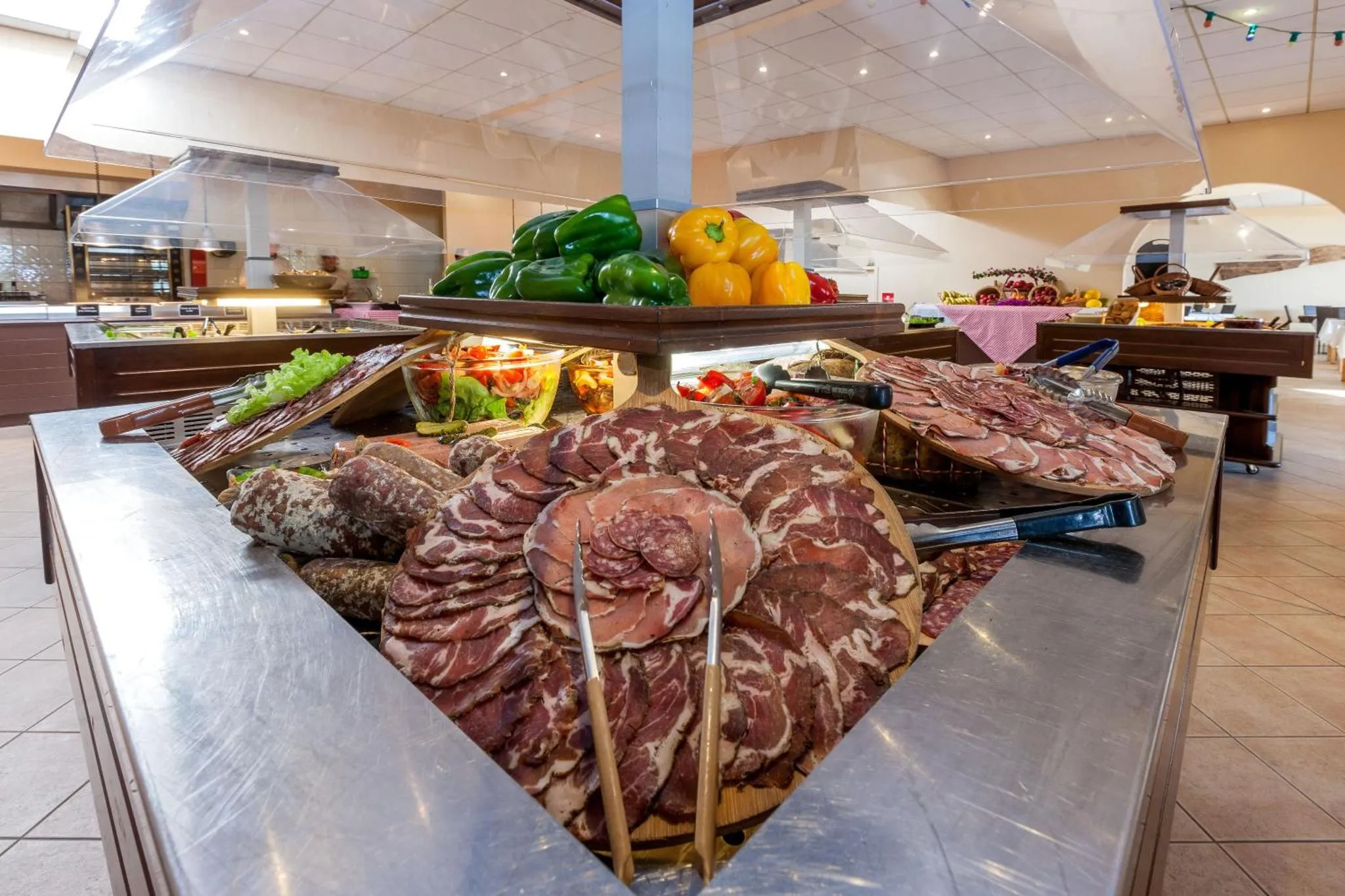 Un buffet propose une grande variété de charcuteries et de salades colorées.