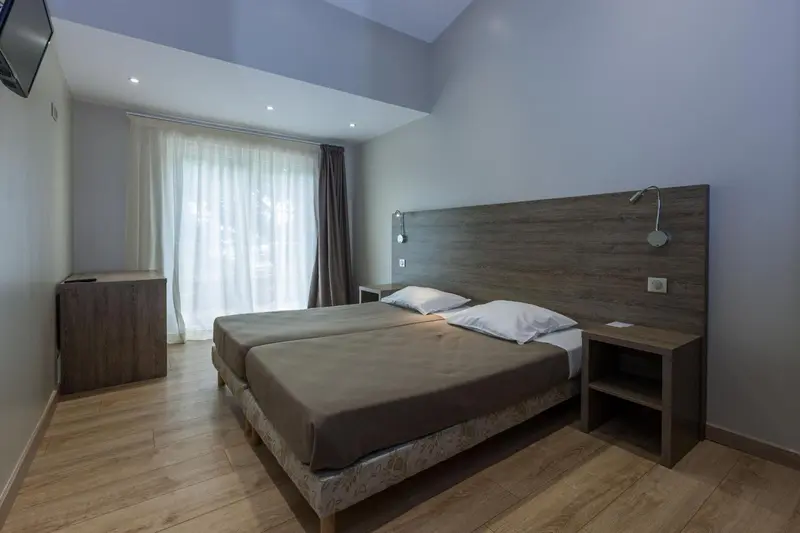 Une chambre lumineuse avec un grand lit et des rideaux blancs.