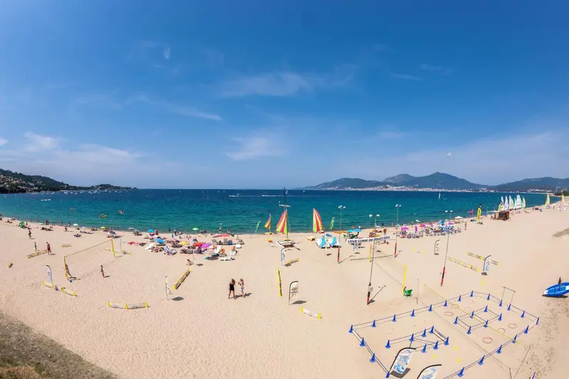 Une plage de sable fin bordée d'une mer turquoise sous un ciel bleu.