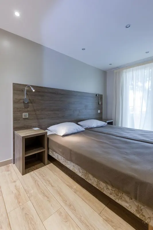 Une chambre lumineuse avec un grand lit et des tables de chevet en bois.