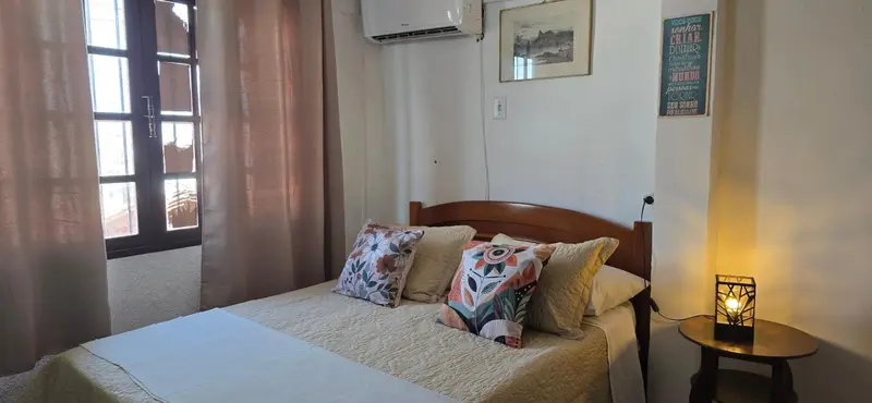 Une chambre lumineuse avec un lit recouvert d'une courtepointe et de coussins.