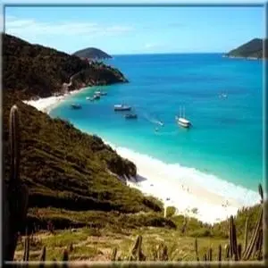 Une plage de sable blanc bordée d'une eau turquoise et entourée de collines verdoyantes.