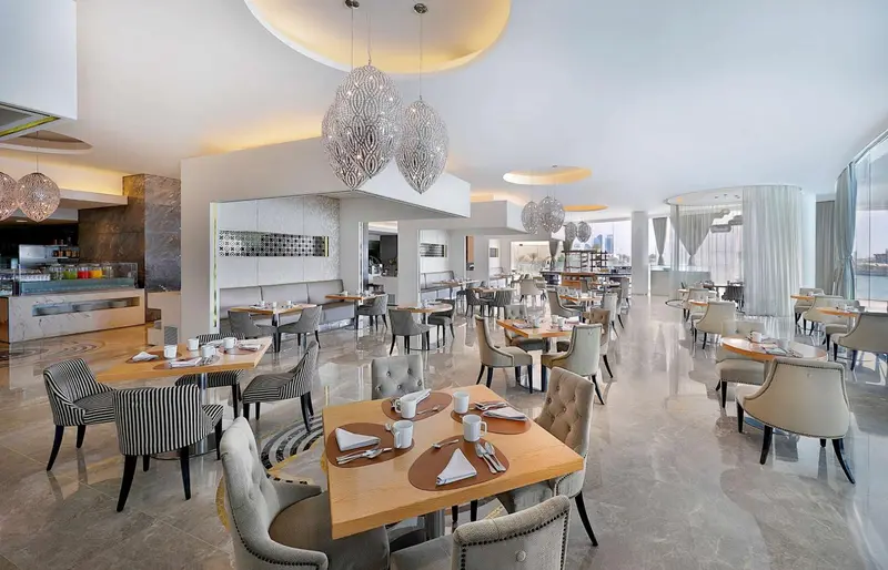 Une salle lumineuse avec des tables dressées pour le repas.
