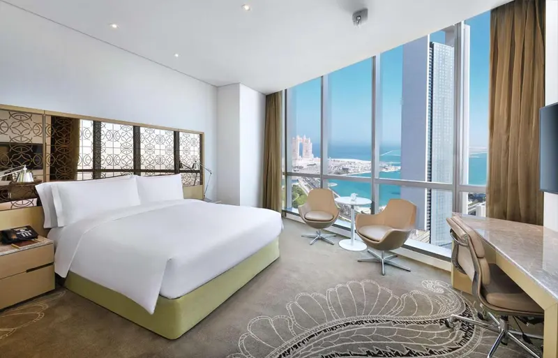 Chambre lumineuse avec un grand lit et une vue sur la mer.