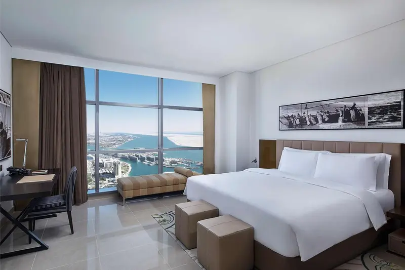 Chambre lumineuse avec un grand lit et une vue sur la mer.