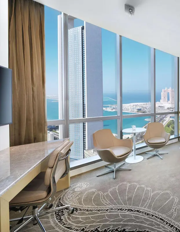 Espace salon avec bureau et vue sur la mer depuis de grandes baies vitrées.