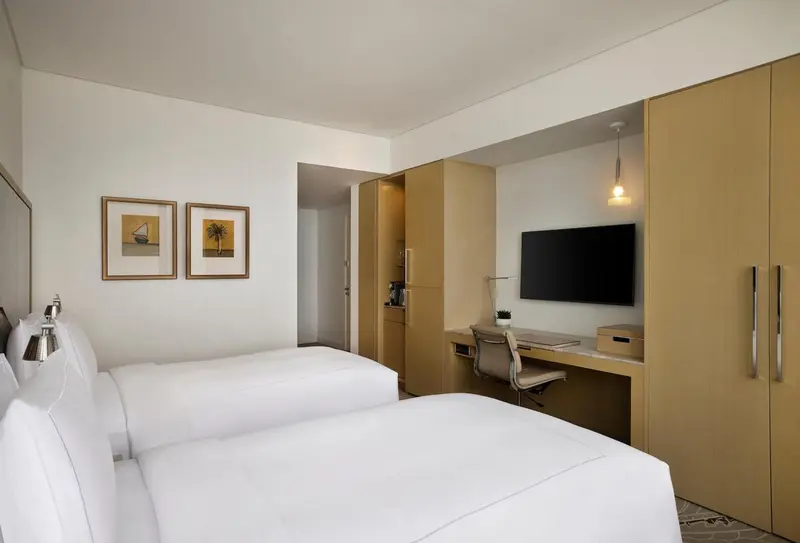 Une chambre d'hôtel lumineuse avec deux lits simples et un bureau.