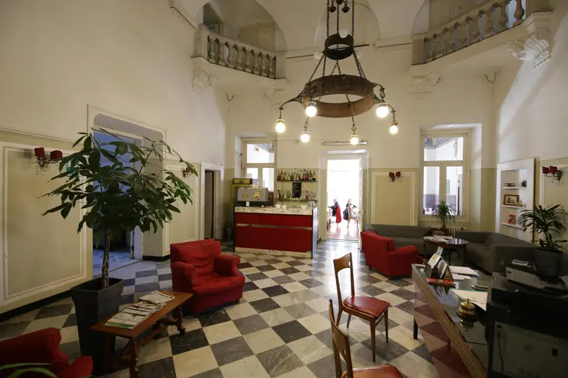 Un hall d'accueil lumineux avec un comptoir et des fauteuils rouges.