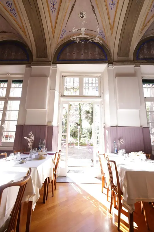 Une salle lumineuse avec des tables dressées pour un repas.