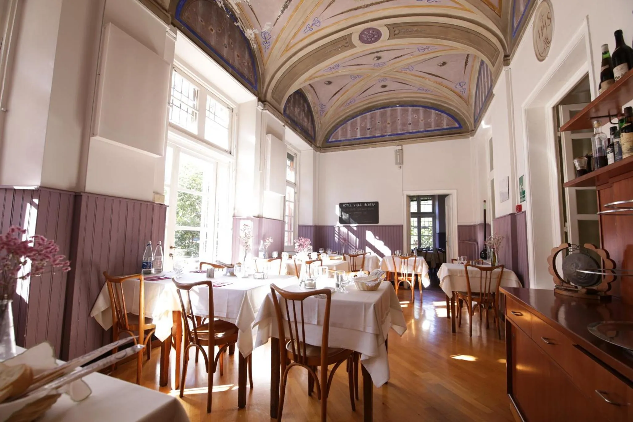 Une salle lumineuse avec des tables dressées pour un repas.