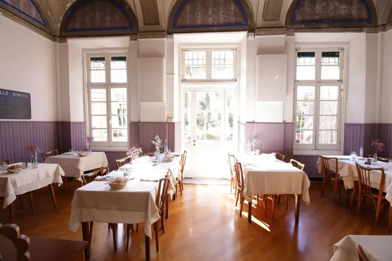 Une salle lumineuse avec des tables dressées pour un repas.