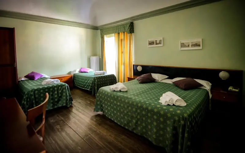 Une chambre avec deux lits simples et un lit double.