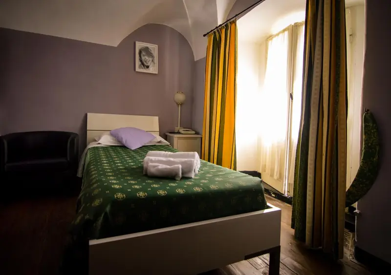Une chambre avec un lit recouvert d'une courtepointe verte et un canapé noir.