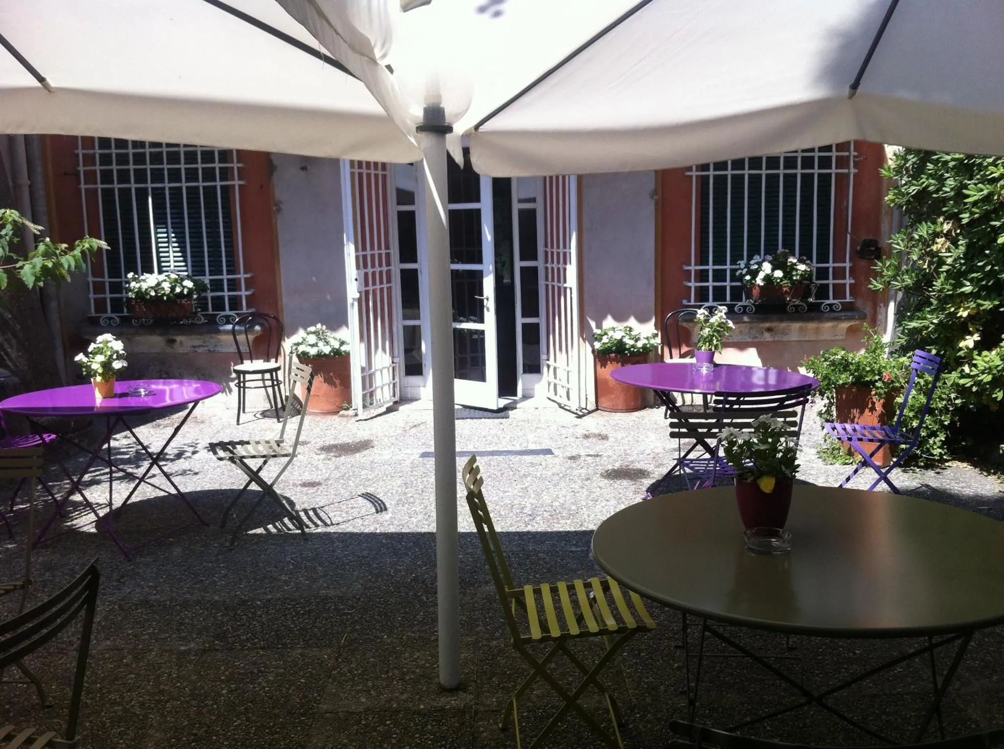 Tables et chaises disposées sur une terrasse pavée ombragée.